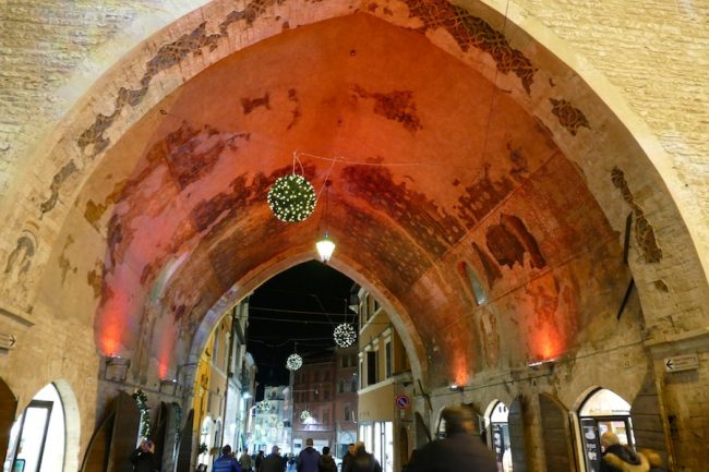 La gente a passeggio sotto l'arco del Podestà
