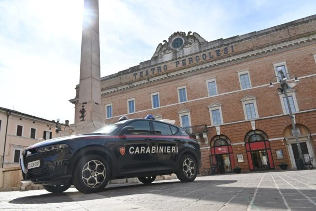 Pattuglia di polizia ferma auto in strada, agente controlla documenti a conducente anziano, immagine di approfondimento